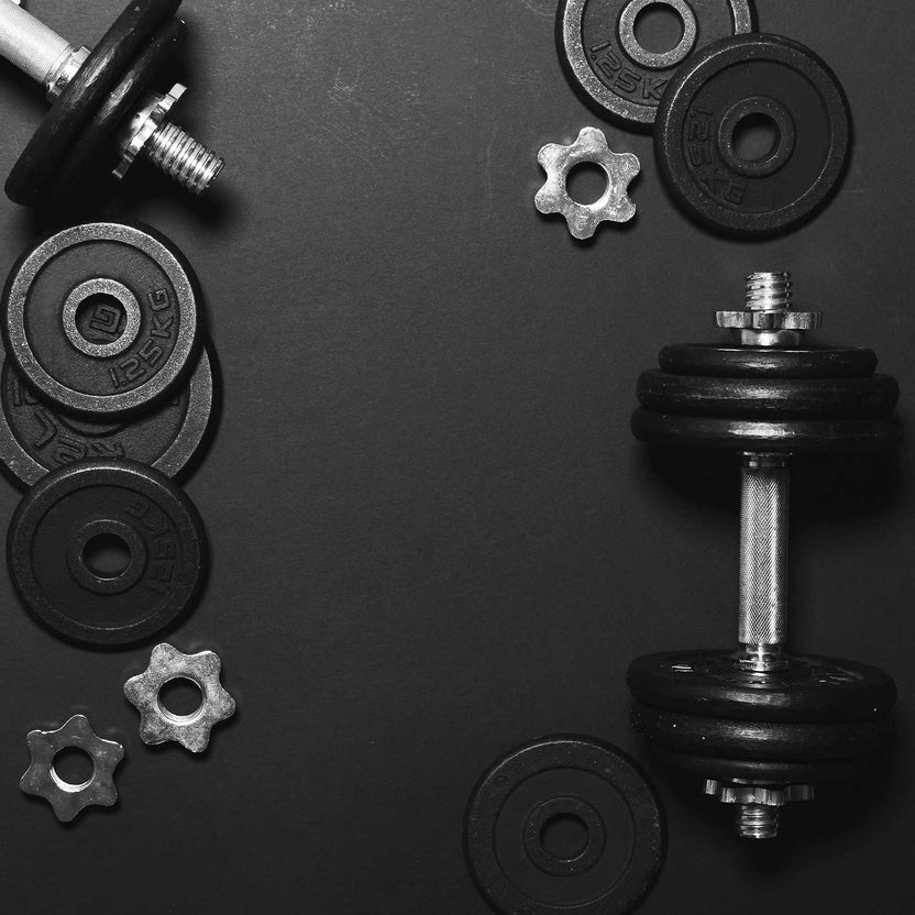 Black dumbbells and weight plates on a dark background